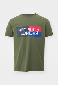 Olīvu zaļš kokvilnas T-kreklu ar lielu grafiku, kurā ir "RED BULL RACING" baltā, sarkanā, zilā un melnā krāsā. Īsas piedurknes un apaļa kakla izgriezums.