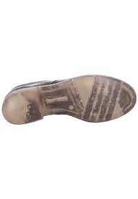 Schuhsohle mit einer strukturierten, beigen GummOberfläche. Enthält Rillen und Muster für besseren Halt, mit sichtbarem Logo-Abdruck. Leicht abgenutztes Aussehen.