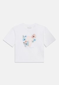 Λευκό βαμβακερό μπλουζάκι με εκτύπωση λουλουδιών και πεταλούδας σε απαλό μπλε και ροζ, με το κείμενο "GUESS Los Angeles" σε ανοιχτό μπλε. Κοντό μήκος.