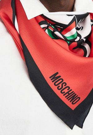 Czerwono-czarny szalik Moschino z graficznym wzorem owinięty wokół szyi osoby noszącej białą koszulę.