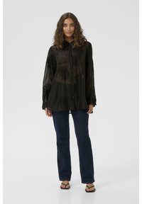 Black sheer shirt with long sleeves, button front, and floral embroidery on the sleeves. Paired with dark blue jeans and black flip-flops.