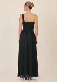 Abito maxi nero con corpetto arricciato, spallina unica e gonna in chiffon fluida. Presenta una silhouette snella e un design fino alla caviglia.