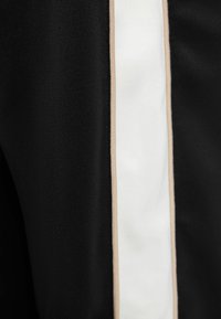 Black fabric featuring a vertical white stripe bordered by a beige accent. The texture appears smooth and uniform.