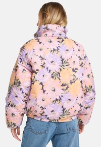Jachetă puffer cu un model floral în culori pastelate, având un guler înalt, manșete elastice și o croială ușor scurtă.