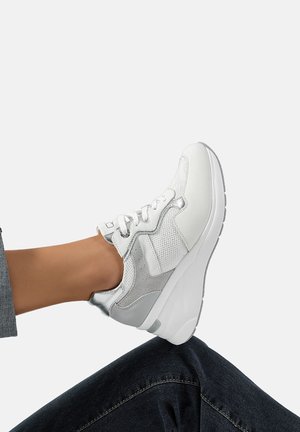 Sneaker bianco con accenti argentati, materiali in rete e pelle liscia, design con lacci e suola spessa e testurizzata.