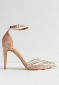 Nude patentläder högklackade sko med ankelrem och spetsig tå. Rena remmar med silverdekorationer pryder ovandelen.