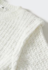 Pull en maille blanche avec un motif tissé texturé et un col ras du cou, plié pour montrer les détails de la manche et du tissu.