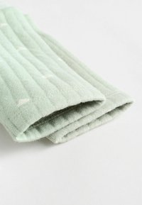 Jasnozielony materiał z ryżowym wzorem, z małymi białymi wzorami chmur. Produkt jest starannie złożony, ukazując miękką, dzianinową tkaninę.