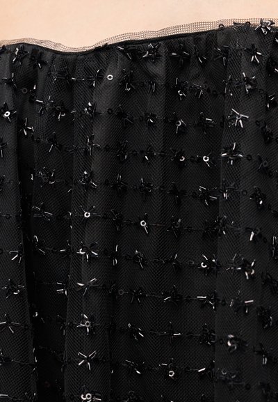 Close-up of black sheer fabric adorned with small black bead and sequin floral embellishments.