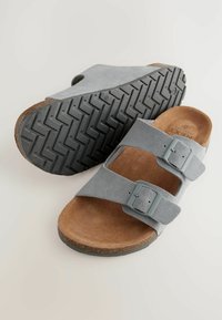 Grå ruskinds slide-sandaler med to justerbare spænder, korkfodersåler og mønstret gummiydersål. Letvægts og komfortabelt design.