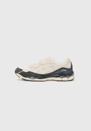 Kremowo-czarny but do biegania ASICS z cholewką z siateczki, gumową podeszwą i widocznym amortyzowaniem na jednolitym jasnym tle.