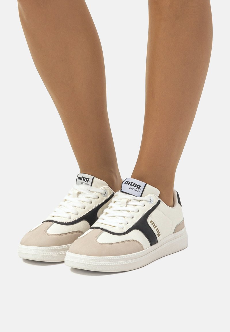 Sneakers bianchi e beige con accenti neri, dotati di una tomaia in pelle liscia, pannello in suede testurizzato e lacci tradizionali.