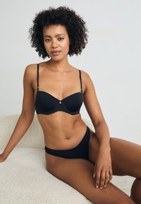 Black bra and matching brief set with smooth fabric, underwire support, adjustable straps, and minimalistic design.