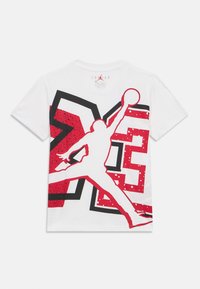 Άσπρο βαμβακερό t-shirt με κόκκινο και μαύρο γραφικό που απεικονίζει έναν παίκτη μπάσκετ σε άλμα, με έντονες μορφές και φόντο με πουά.