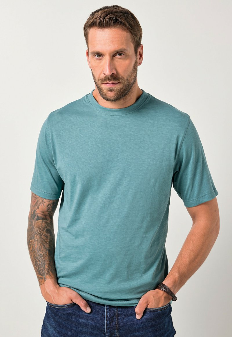 Krátký rukáv, kulatý výstřih, tričko v odstínu teal, vyrobené z lehké, texturované látky. Má uvolněný střih a minimalistický design.