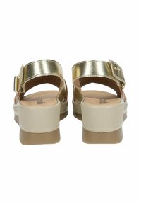 Sandali con cinturino metallico dorato, suola a cuneo beige e soletta imbottita. La fibbia regolabile sul cinturino aggiunge funzionalità. Suola testurizzata.
