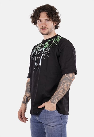 T-shirt di cotone nero con grafiche di fulmini verdi e bianchi sulla parte anteriore. Vestibilità rilassata con maniche corte e collo a giro.