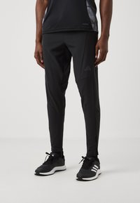 Zwarte sportbroek gemaakt van een lichtgewicht materiaal met een slim fit, met subtiele branding en een taps toelopend ontwerp voor ventilatie.