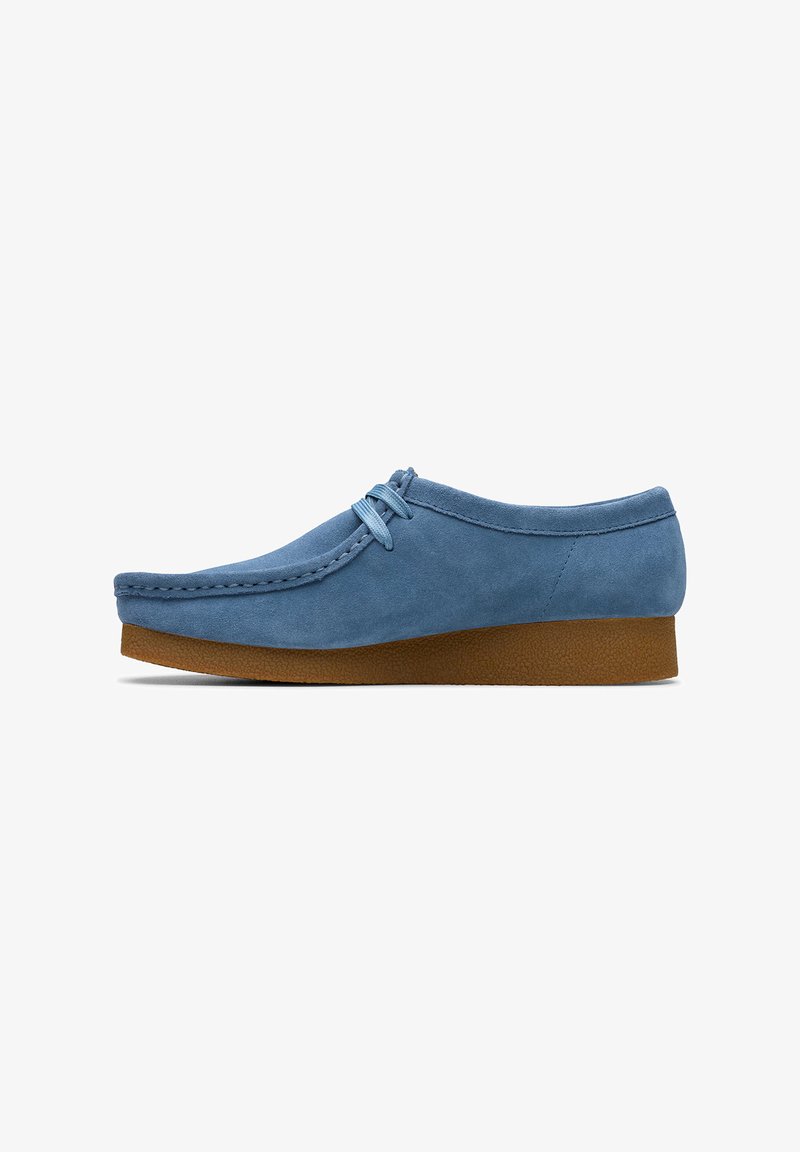 Chaussure en daim bleu clair avec un bout arrondi, des détails cousus et une semelle en caoutchouc. Caractérisée par un laçage et un talon bas en coin.