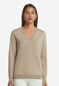Beige V-Ausschnitt-Pullover aus weichem Strick mit langen Ärmeln und gerippten Bündchen. Leichte Textur mit einer entspannten Passform, die sich gut zum Schichten eignet.