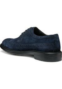 Zapato de vestir de ante azul marino con detalles de brogue, punta redonda, diseño con cordones y suela de goma negra texturizada.