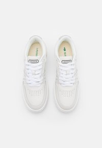 Valged nahast spordijalatsid perforatsioonide/detailidega, helesiniste triipudega ja must Lacoste logo keelel.