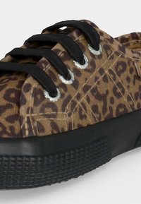 Καφέ αθλητικό παπούτσι με μαύρο λεοπάρ σχέδιο, μαύρα κορδόνια περασμένα από ασημένιες τρύπες και υφασμένη μαύρη καουτσούκ σόλα.