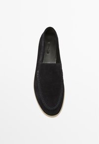 Scarpa slip-on in suede di un navy scuro con cuciture blu a contrasto, design minimalista e suola in gomma per comfort e flessibilità.