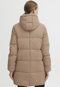 Beige puffer coat with a hood, featuring a quilted design and long sleeves. The coat extends to mid-thigh and has a smooth texture.