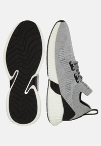 Grå stickade träningsskor med svarta accenter, med en texturerad vit gummisula, snörningsdesign och en stödjande hög toppstruktur.