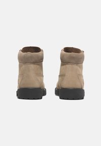 Stivaletti alla caviglia in pelle tan con una finitura in suede morbido, punta rotonda e suole in gomma nera. Presentano dettagli cuciti e un colletto imbottito.