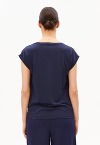 Marineblauw T-shirt met korte mouwen van zachte stof, met een losse pasvorm, ronde halslijn en opgerolde mouwzomen, gezien vanaf de achterkant.