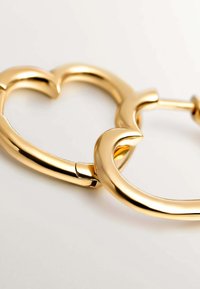 Pendientes de aro de oro con una superficie lisa y brillante, que presentan un diseño curvado que se entrelaza en la bisagra, creando un acento elegante.