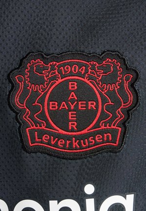 Musta kangaspalikka, jossa on Bayer Leverkusenin logo, punaisin kirjailtuin leijonin ja tekstit "1904" sekä "BAYER Leverkusen". Kohokuvioitu tausta.