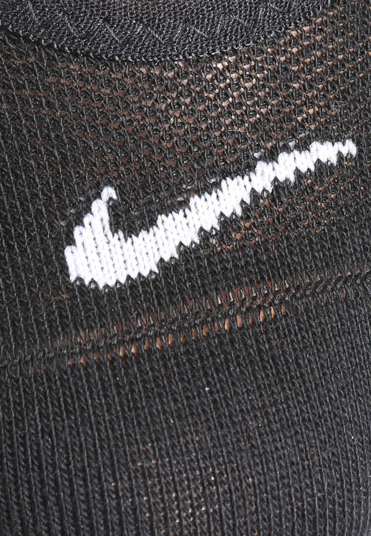Svart sportstrumpa med en vit broderad Nike-logotyp, tillverkad i ett texturerat tyg och med en snug passform runt vristen.
