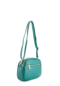 Tyrkisfarvet lædertaske med to lynlåslommer og en glat tekstur. Har guldfarvet hardware og en justerbar rem.