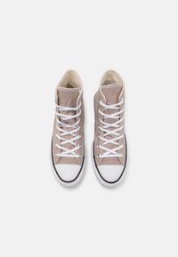 High-top sneakers in light beige canvas with white laces, black rubber soles, and white toe cap detailing.