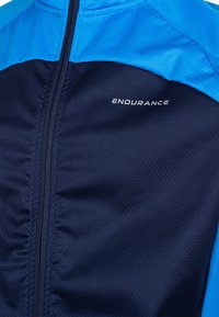 Marineblau und blaue Sportjacke mit strukturierter Oberfläche, durchgehendem Reißverschluss auf der Vorderseite und dem auffällig platzierten "ENDURANCE"-Logo auf der Brust.