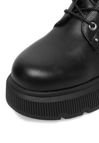 Czarne skórzane botki za kostkę z okrągłym noskiem, teksturowaną gumową podeszwą i czarnymi sznurówkami. Posiadają oczka oraz gładkie wykończenie.