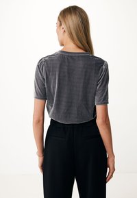 Grijze fluwelen cropped top met korte mouwen, met gerimpelde schouders en een ronde hals, gecombineerd met zwarte hoog in de taille gelegen broek.