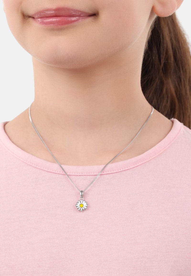 Collana in argento con ciondolo a margherita con un fiore bianco e centro giallo, indossata sopra una maglietta a collo rotondo di un rosa chiaro.