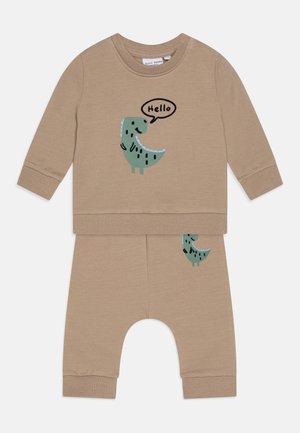 Beige babyoutfit med lange ærmer med grøn dinosaurgrafik, der siger "Hello" på toppen og matchende bukser med en mindre dinosaurusdetalje.
