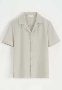 Chemise à manches courtes en tissu beige clair, avec un col plat, cinq boutons sur le devant et un ourlet droit.