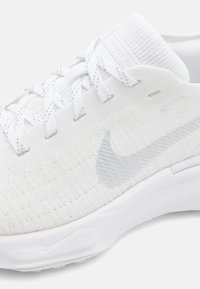 Scarpa da corsa bianca con tomaia in maglia testurizzata, sistema di lacci piatto, logo swoosh traslucido e intersuola bianca ammortizzata.