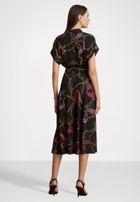 Čierne šaty s vzorom reťaze a stuhy, krátkymi rukávmi, zúženým pásom a splývavou sukňou strednej dĺžky. Nosené s čiernymi opätkami.