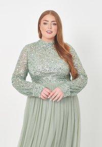 Mintgrünes Langarmkleid mit einem bestickten Oberteil und transparenten langen Ärmeln, fließendem, plissiertem Rock und hohem Kragen. Spinatgrüne Farbe.
