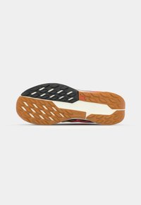 Rubber sole with a textured pattern; features black, white, and orange segments; designed for traction and durability.