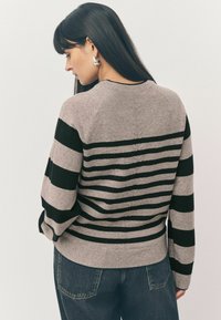 Pull rayé gris avec des bandes horizontales noires, manches ribbed aux poignets et en bas, présentant un col rond et des manches raglan.