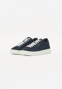 Marineblå semskede sneakers med hvite snørebånd, har en rund tå, minimalistisk design og en hvit gumm såle. Inkluderer liten merkevaredetalj.