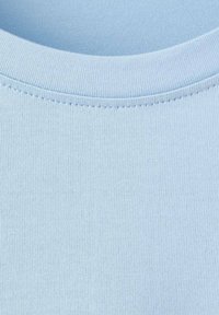 Světle modrá tkanina trička s kulatým výstřihem, hladká textura s jemným žebrováním. Bez viditelných vzorů či ozdob.